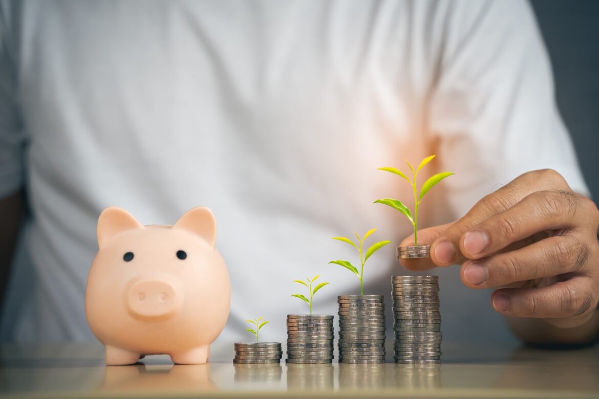 man investort hand putting coin in piggy bank. Saving money conc